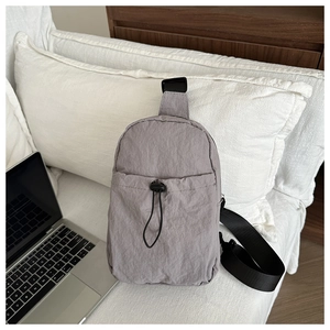 Detail of light purple nylon crossbody bag with adjustable drawstring on a white sofa