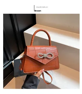 Detail of a brown croc-embossed handbag featuring a sparkling rhinestone bow buckle