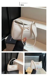 Detail of white baguette bag with golden bow buckle and lychee grain texture