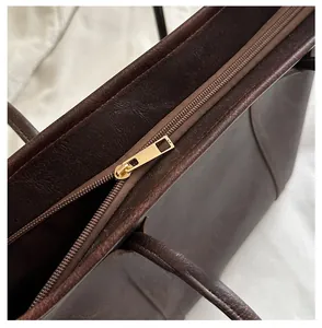 Dettaglio della cerniera in metallo dorato su una borsa tote vintage in pelle marrone scuro