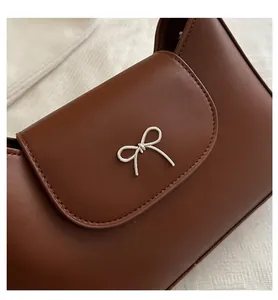 Close-up of dark brown leather handbag featuring a vintage silver metal bow accessory