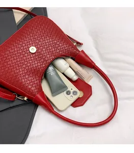 Detalle del bolso tejido rojo que muestra la capacidad interior y el cierre magnético dorado
