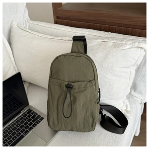Detail of olive green nylon crossbody chest bag with drawstring pocket on office desk