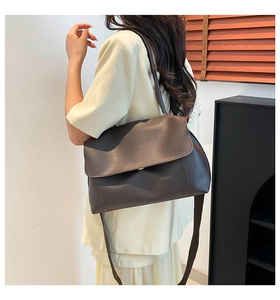 Detailed side view of a large dark brown leather shoulder bag shown on a female model