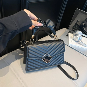 Black V-quilted shoulder bag with ruched handle and gold square clasp on grey surface