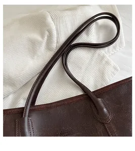 Vista dettagliata della borsa tote in ecopelle marrone scuro con manico e logo stampato
