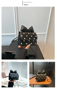 Detail view of mini black polka dot shoulder bag with large bow decoration and strap