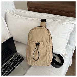 Detail of khaki nylon sling bag with drawstring pocket and black adjustable strap