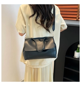 Close-up of minimalist black leather tote bag back view with wide shoulder strap
