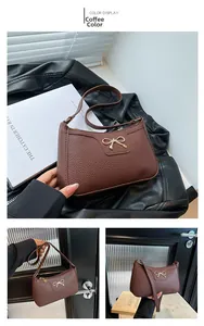 Detail of coffee brown pebble leather shoulder bag with a metal bow accent and zipper