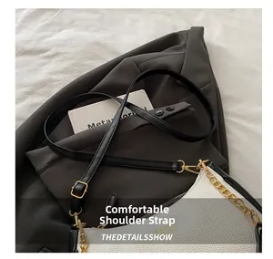 Detail of white lychee pattern leather bag with gold chain and black shoulder strap