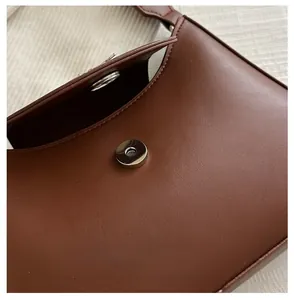 Detailed shot of silver magnetic snap closure on dark brown leather shoulder bag