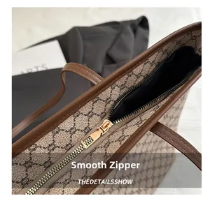 Detail of a smooth golden metal zipper closure on a stylish tote bag with vintage patterns