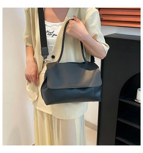 Detail of black matte PU tote bag with wide fabric strap on person for size view
