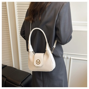 Close-up of woven beige texture and metallic M logo on a crescent-shaped shoulder bag
