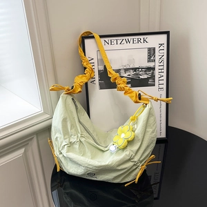 Light green pleated dumpling bag with yellow ruched shoulder strap and flower charm