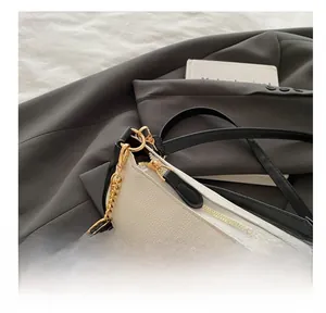 Close-up of white litchi pattern leather bag with smooth gold zipper and hardware details