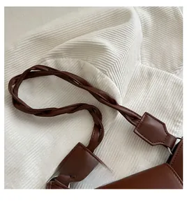 Detailed macro view of the brown leather shoulder bag with a braided twist handle design