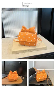 Detail view of mini orange polka dot crossbody bag with a large bow and strap