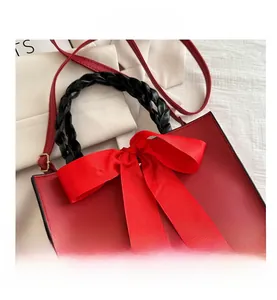 Detail view of red bridal handbag with large silk bow and braided black handle