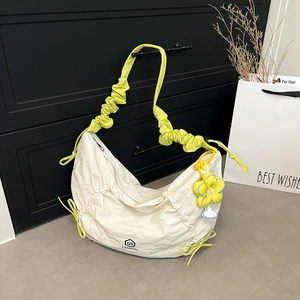 White pleated crossbody bag with yellow strap and flower charm in minimalist setting