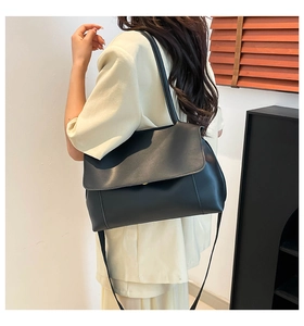 Detailed view of the large black leather tote bag worn by a model in a minimalist interior