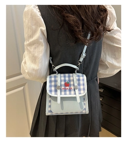 Close-up of plaid handbag with apple pattern and adjustable strap on a model back