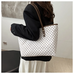 Detail view of large tote bag with vintage pattern and brown leather straps on a model