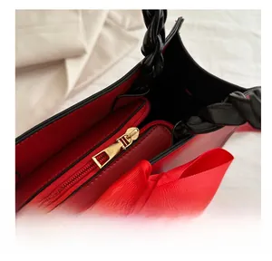 Close-up of a red handbag featuring a gold zipper and a large silk bow decoration