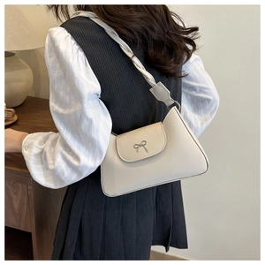 Chic cream white underarm bag with a metal butterfly bow and twisted woven strap