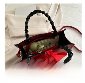 Detail view of red leather handbag interior capacity with silk bow and woven handle