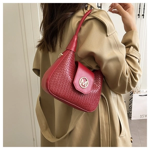Detailed view of woven red leather shoulder bag with gold M metal buckle on a model