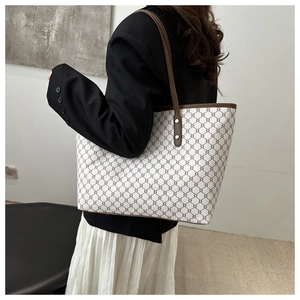 Detail view of large white and brown geometric monogram tote bag worn on the shoulder