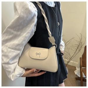 Detail of cream vintage underarm bag featuring a silver bow buckle and braided shoulder strap