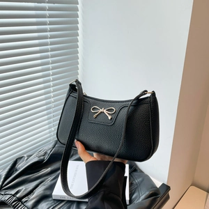 Chic black litchi pattern baguette bag with gold bow hardware for minimal summer outfits