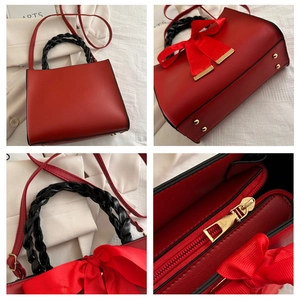 Detail of red leather handbag showing woven handles, gold zipper and protective metal studs