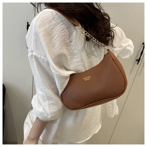 Detail of brown lychee leather crescent bag with gold chain strap and fashion text