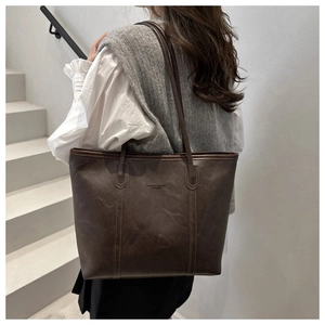 Dettaglio della borsa tote vintage in pelle marrone con testo goffrato e cuciture