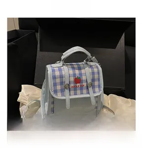 Detailed close-up of light blue checkered handbag with dual straps and apple logo design