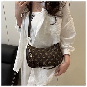 Detail of retro monogram underarm bag with contrast leather strap and gold chain strap