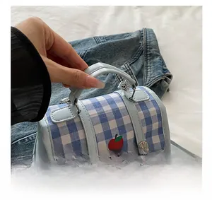 Detail view of light blue checkered handbag with apple print and premium metal hardware