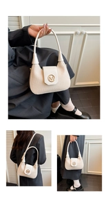 Detail of cream woven crescent bag showing the gold M buckle and fine braided texture