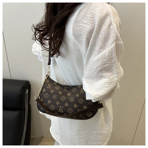 Detail shot of vintage pattern underarm bag with gold chain strap on a model