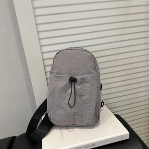 Minimalist grey nylon crossbody bag with drawstring front pocket and black strap