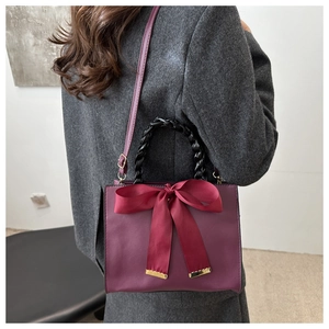 Detail of red bridal handbag featuring elegant bow and black woven ring handle