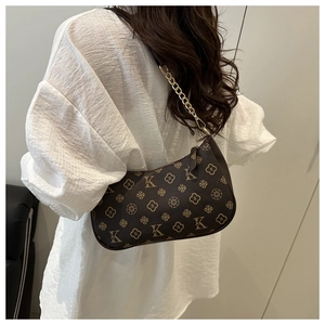Close-up of vintage brown printed underarm bag with gold chain and monogram pattern