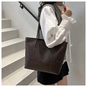 Dettaglio della borsa tote vintage marrone scuro con logo a rilievo e trama in pelle