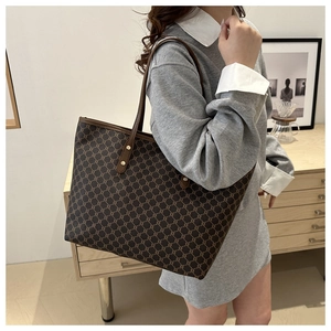 Detail of the vintage monogram tote bag with leather straps on a female model's shoulder