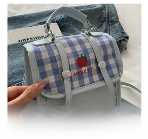 Close-up of blue plaid handbag with red apple embroidery and adjustable strap detail