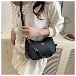 Detail of black crescent crossbody bag with lychee texture and gold chain strap